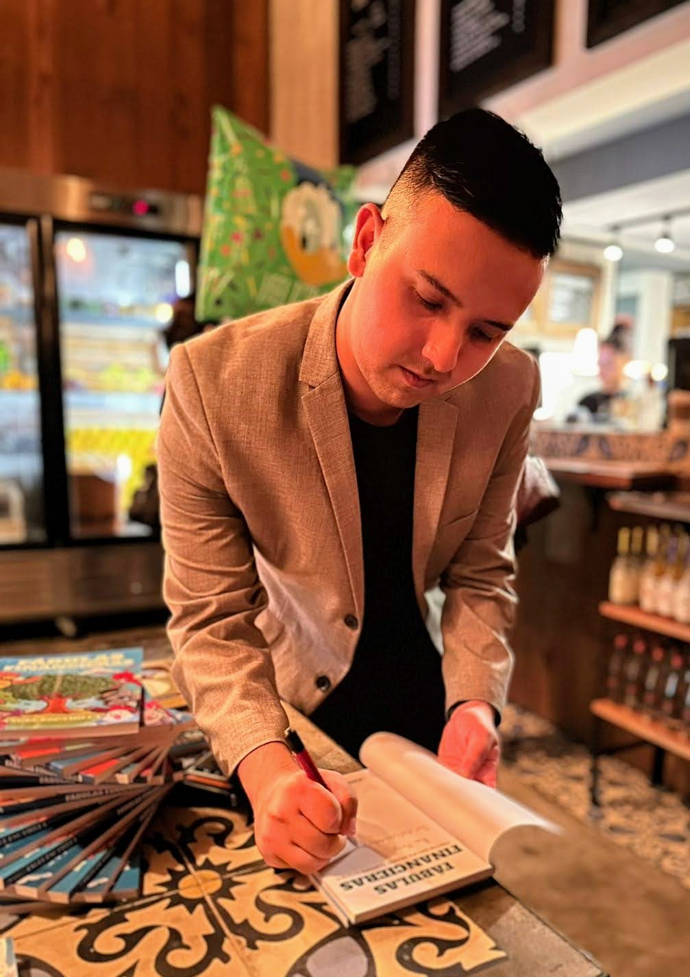 Angel Escamilla firmando un ejemplar de Fábulas Financieras en evento de presentación de libro